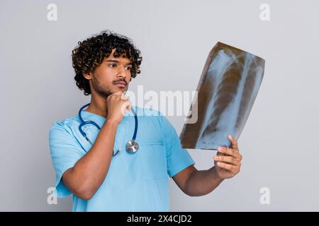 Photo du médecin réfléchi Guy tient un regard de rayons X pensant un fond de couleur grise isolé Banque D'Images