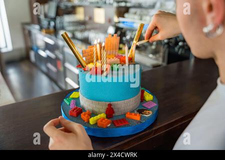 Gâteau fondant bleu avec des bougies allumées et des pièces de construction. Huit ans. Banque D'Images