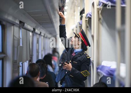 (240502) -- URUMQI, 2 mai 2024 (Xinhua) -- Airkir Duliki travaille sur un train de Kashgar à Chengdu en Chine, 18 avril 2024. Airkir Duliki, le chef de train tadjik âgé de 27 ans, est né et a grandi au milieu des montagnes enneigées et des prairies dans un village du comté autonome tadjik de Taxkorgan sur le plateau du Pamir, où les chemins de fer n'étaient pas courants pour les résidents dans le passé. La première expérience d'Airkir avec le voyage en train s'est produite quand elle s'est rendue à Urumqi pour l'université au Xinjiang. Accompagnée de son père, elle a parcouru plus de 300 kilomètres de terrain montagneux depuis leur village Banque D'Images