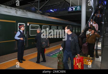 (240502) -- URUMQI, 2 mai 2024 (Xinhua) -- Airkir Duliki (1er l) aide les passagers à monter à bord d'un train de Chengdu à Kashgar à une gare de Guangyuan, province du Sichuan, au sud-ouest de la Chine, le 20 avril 2024. Airkir Duliki, le chef de train tadjik âgé de 27 ans, est né et a grandi au milieu des montagnes enneigées et des prairies dans un village du comté autonome tadjik de Taxkorgan sur le plateau du Pamir, où les chemins de fer n'étaient pas courants pour les résidents dans le passé. La première expérience d'Airkir avec le voyage en train s'est produite quand elle s'est rendue à Urumqi pour l'université au Xinjiang. Accompagné par elle Banque D'Images