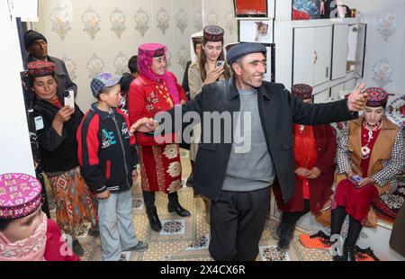 (240502) -- URUMQI, 2 mai 2024 (Xinhua) -- le père d'Airkir Duliki danse quand Airkir Duliki rentre chez lui dans le comté autonome tadjik de Taxkorgan, dans la région autonome ouïgoure du Xinjiang, au nord-ouest de la Chine, le 23 mars 2024. Airkir Duliki, le chef de train tadjik âgé de 27 ans, est né et a grandi au milieu des montagnes enneigées et des prairies dans un village du comté autonome tadjik de Taxkorgan sur le plateau du Pamir, où les chemins de fer n'étaient pas courants pour les résidents dans le passé. La première expérience d'Airkir avec le voyage en train s'est produite quand elle s'est rendue à Urumqi pour l'université au Xinjiang. Accompagné Banque D'Images