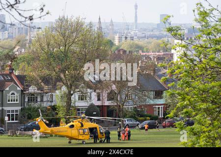 Surveillé par un spectateur, un blessé est pris d'un hélicoptère d'ambulance aérienne à Ruskin Park - un espace public du sud de Londres, pour être emmené par la route au Kings College Hospital voisin à Camberwell, le 1er mai 2024, à Londres, en Angleterre. G-LNAC est un hélicoptère AugustaWestland AW169 exploité par Kent, Surrey & Sussex Air Ambulance. Banque D'Images