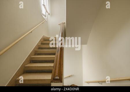 Escaliers intérieurs d'une maison unifamiliale avec balustrades en briques avec mains courantes en bois et marches en béton Banque D'Images