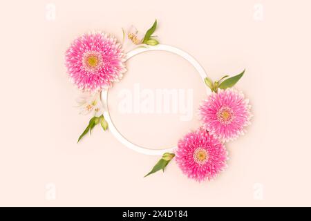 Couronne faite de feuilles vertes, fleurs d'alstroemeria et de gerbera sur fond beige. Banque D'Images