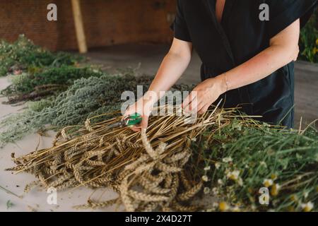 Femme fabriquant une couronne naturelle dans un atelier rustique Banque D'Images