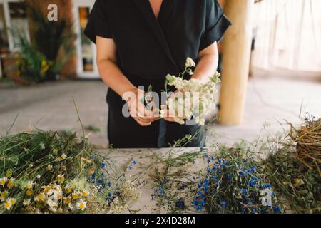 Femme fabriquant une couronne naturelle dans un atelier rustique Banque D'Images