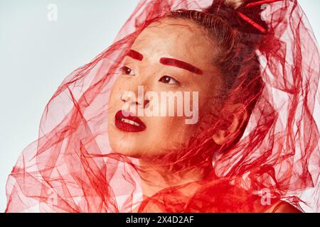 Femme asiatique pose portant un voile rouge vif. Banque D'Images
