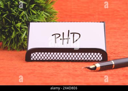 Word PhD. Docteur en philosophie. DOCTORAT sur une carte de visite blanche fournie avec un stylo plume et des plantes en combinaison Banque D'Images