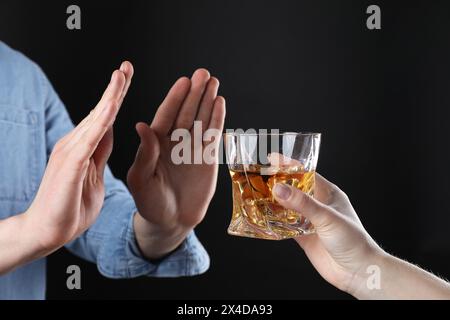 Alcoolisme. Homme refusant le verre de whisky sur fond sombre, gros plan Banque D'Images