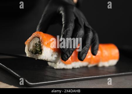 Chef en gants faisant des rouleaux de sushi à la table grise, gros plan Banque D'Images