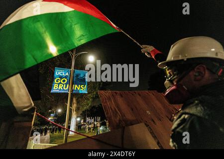 Les manifestants pro-palestiniens regardent les forces de police de la zone depuis le campement construit devant Royce Hall à UCLA. Banque D'Images