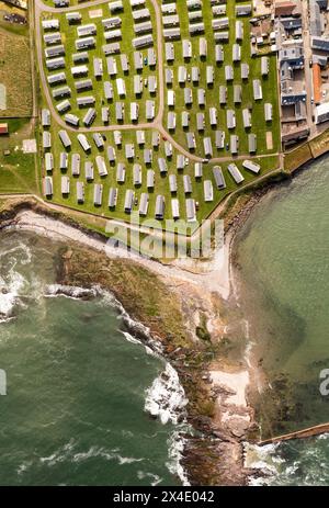 Vue aérienne de haut en bas d'un grand groupe de caravanes statiques sur un parc de caravanes ou un site de maisons de vacances sur la côte dans une station balnéaire pour des vacances en famille Banque D'Images