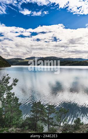 Vue sereine sur Tingvollfjorden en Norvège, avec des eaux calmes avec des reflets sous un ciel nuageux bleu d'été. Banque D'Images