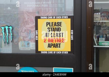 S'il vous plaît rester à au moins 2 mètres de distance, signer sur une porte de magasin, centre-ville de Sheffield, Angleterre Royaume-Uni, en prenant soin les uns des autres rester en sécurité restrictions COVID Banque D'Images