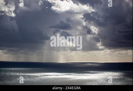 Ciel gris couvert avec des nuages texturés bas. La lumière du soleil jette un œil à travers les nuages et tombe sur la mer. Arrière-plan. Horizontal Banque D'Images