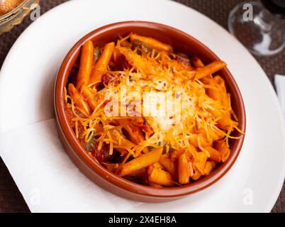 Pâtes cuites au four avec chistorra, poivre, oignon et croûte de fromage croustillante. Banque D'Images