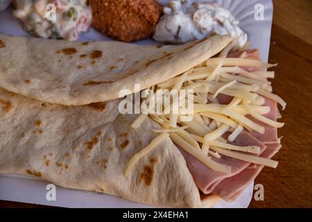 Une crêpe dorée salée fourrée de jambon et de fromage fondu offre une délicieuse combinaison de saveurs. Banque D'Images