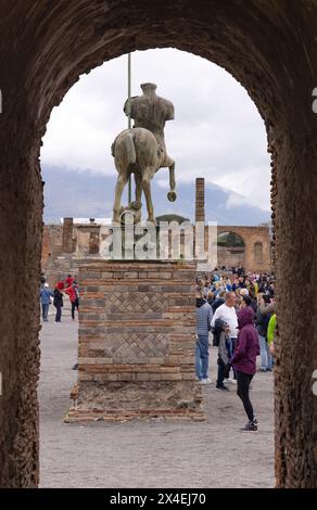 Forum Pompéi. Visiteurs à la statue Centaure vue à travers l'arc d'Auguste, Forum de Pompéi ruines romaines, civilisation antique, Pompéi Italie Banque D'Images