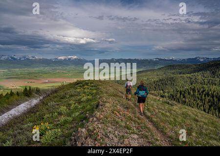 États-Unis, Idaho. Couple randonnée sur sentier dans les montagnes Big Hole avec vue sur les montagnes Teton et la vallée. Banque D'Images