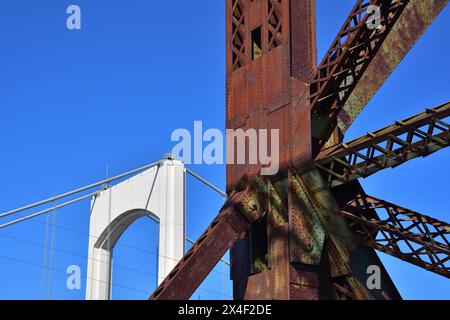 Ancienne structure de pont riveté en acier rouillé versus pont suspendu plus récent. Banque D'Images