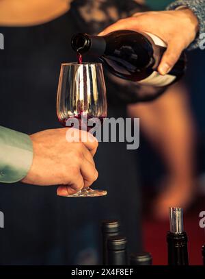 États-Unis, État de Washington, Walla Walla. Femme verse du vin rouge dans un verre lors d'un événement de vin à Walla Walla. Banque D'Images