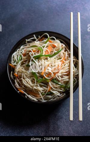 Gros plan sur les nouilles schezwan ou chow mein, une recette indo-chinoise populaire servie dans un bol avec des baguettes en bois. Banque D'Images