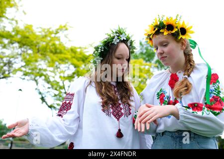 belles jeunes femmes filles tissage couronnes marche rire bavarder dans le parc dans le jardin brodé national ukrainian chemises couronnes de fleurs de tournesol et forêt blanc fleurs magnifique vyshyvanka Banque D'Images