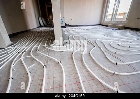 Vue en angle bas sur les tubes blancs minces courbés dans la courbe complexe du nouveau collecteur de système de distribution en laiton monté pour le plancher de chauffage central dans une résidence Banque D'Images