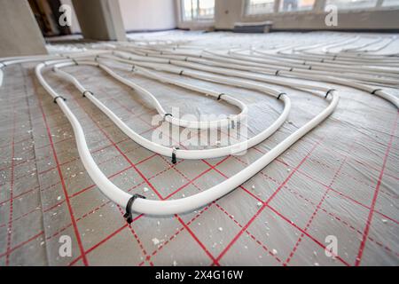 Vue en angle bas sur les tubes blancs minces courbés dans la courbe complexe du nouveau collecteur de système de distribution en laiton monté pour le plancher de chauffage central dans une résidence Banque D'Images