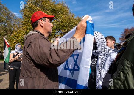 Un contre-manifestant agite un drapeau israélien sur les manifestants lors d'une manifestation pro-palestinienne sur le campus de l'Université de Melbourne. Le pro-israélien porte une casquette Make America Great Again. Melbourne, Victoria, Australie. Banque D'Images