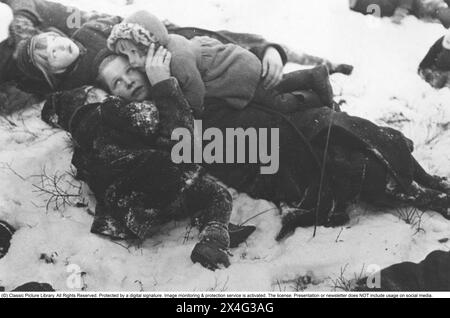 Finlande de la seconde Guerre mondiale. La population civile finlandaise souffre des bombardements de villes et de villages. Voici une mère avec ses enfants regardant anxieusement le ciel. Ses enfants mentent près d'elle et ont peur. Finlande 1940 Banque D'Images