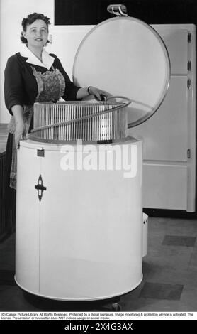 Une femme dans un congélateur d'un design étrange et forme ronde 1955. Les aliments surgelés seraient le début d'une révolution dans les habitudes domestiques et le stockage des aliments. Beaucoup étaient sceptiques, et en particulier les fabricants d'aliments en conserve considéraient les aliments congelés comme une tendance passagère. Banque D'Images