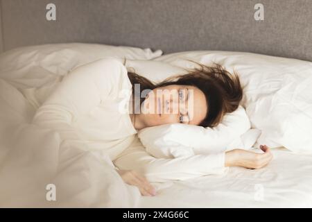 Portrait of young woman lying on bed Banque D'Images