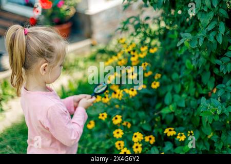 Un enfant examine une fleur sous une loupe Banque D'Images