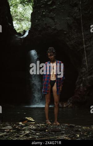 Une jeune femme met des vêtements après avoir nagé dans une cascade. Banque D'Images