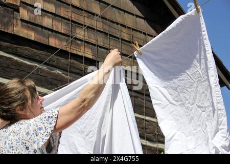 Femme accroche le linge frais sur une ligne au soleil Banque D'Images
