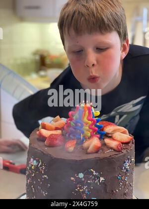 Garçon souffle des bougies sur un gâteau d'anniversaire festif au chocolat Banque D'Images