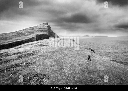 Un homme solitaire marche le long du bord de la falaise sur Vagar, îles Féroé Banque D'Images