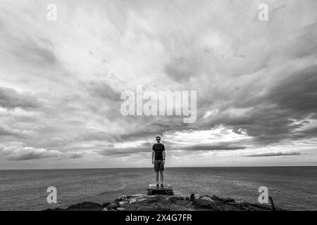 Homme en short se tient sur le bord de la falaise en face de l'océan Pacifique Banque D'Images