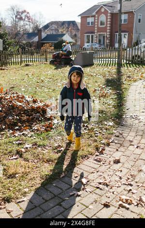 Jeune enfant garçon asiatique dans la cour avant de la maison dans le quartier en automne Banque D'Images