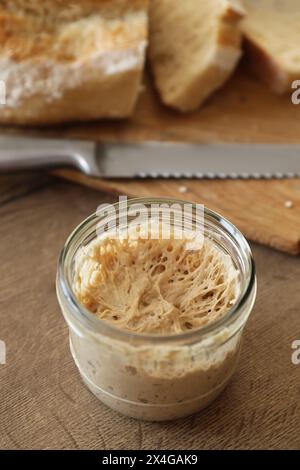 Levain de levain dans un bocal en verre sur une table en bois Banque D'Images