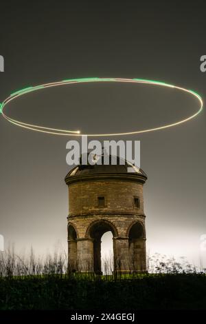 Photo longue exposition d'une tour historique avec un cercle lumineux de drone lumineux au-dessus dans l'obscurité Banque D'Images