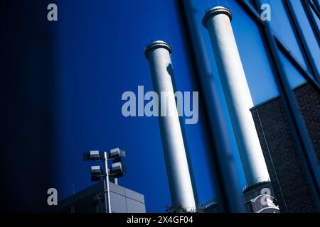 Berlin, Allemagne. 03 mai 2024. Les cheminées se reflètent dans les fenêtres à côté du bâtiment principal de la société de chauffage urbain Vattenfall. Crédit : Carsten Koall/dpa/Alamy Live News Banque D'Images