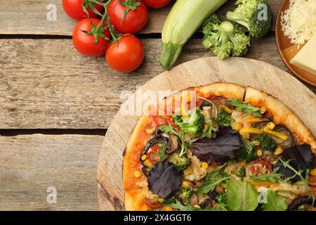 Délicieuse pizza végétarienne et ingrédients sur la table en bois, vue de dessus. Espace pour le texte Banque D'Images