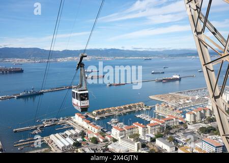 Un téléphérique approche d'une station sur le rocher de gibraltar avec un panorama de Gibraltar Town, la baie de Gibraltar et l'Espagne au loin Banque D'Images