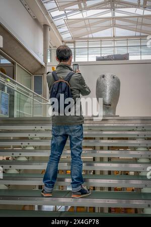 Nîmes, France - 04 17 2024 : vue d’un visiteur prenant une photo avec son téléphone portable depuis l’escalier principal du carré d’Art, muse de l’art contemporain Banque D'Images