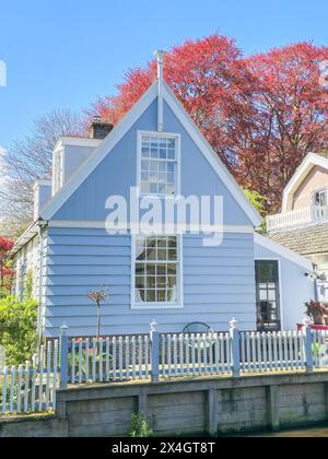 Une charmante maison bleue avec une clôture de piquet blanche debout paisiblement sous un ciel bleu clair, rayonnant de chaleur et de confort. Broek in Waterland Netherlands 21 avril 2024 Banque D'Images