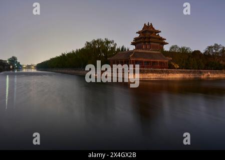 Tour nord-est de la Cité interdite reflétant dans les douves d'eau pendant la nuit calme à Pékin, capitale de la Chine Banque D'Images