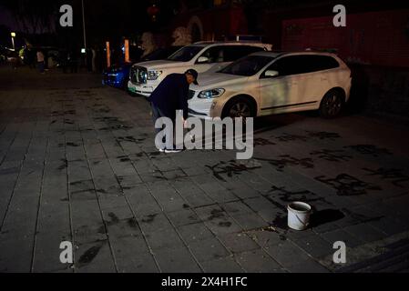 Homme pratiquant la calligraphie de l'eau (écriture au sol - dishu), passe-temps populaire parmi les Chinois retraités, à Pékin, Chine le 18 avril 2024 Banque D'Images
