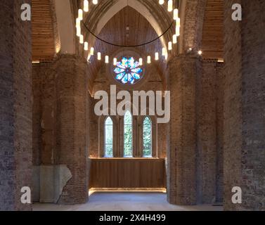 Fenêtre gothique voûtée avec vue sur le cimetière. Abney Park Chapel, Londres, Royaume-Uni. Architecte : Kaner Olette Architects, 2023. Banque D'Images